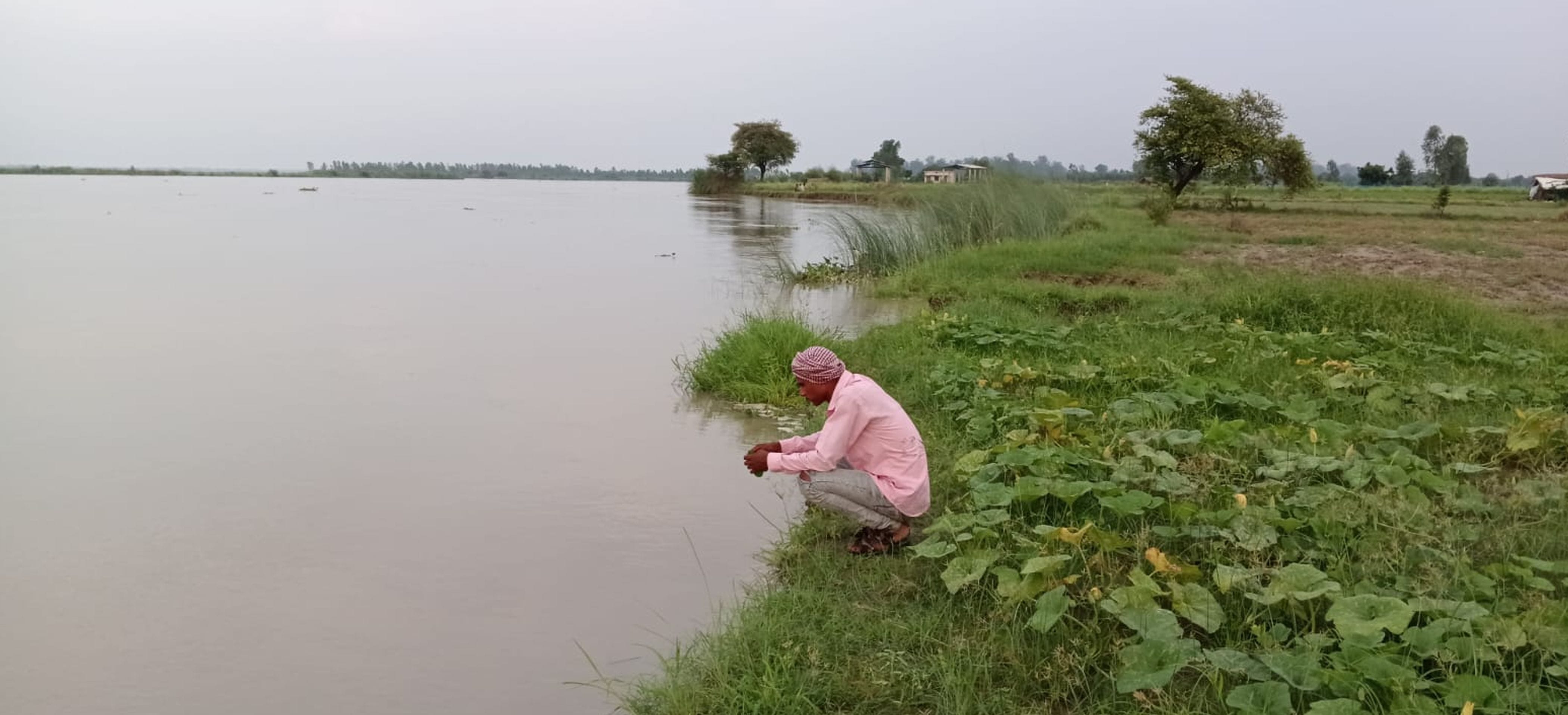 फोटो-49-गंगा और पांडु नदी में बढ़ते जलस्तर से चिंता में बैठा किसान। संवाद