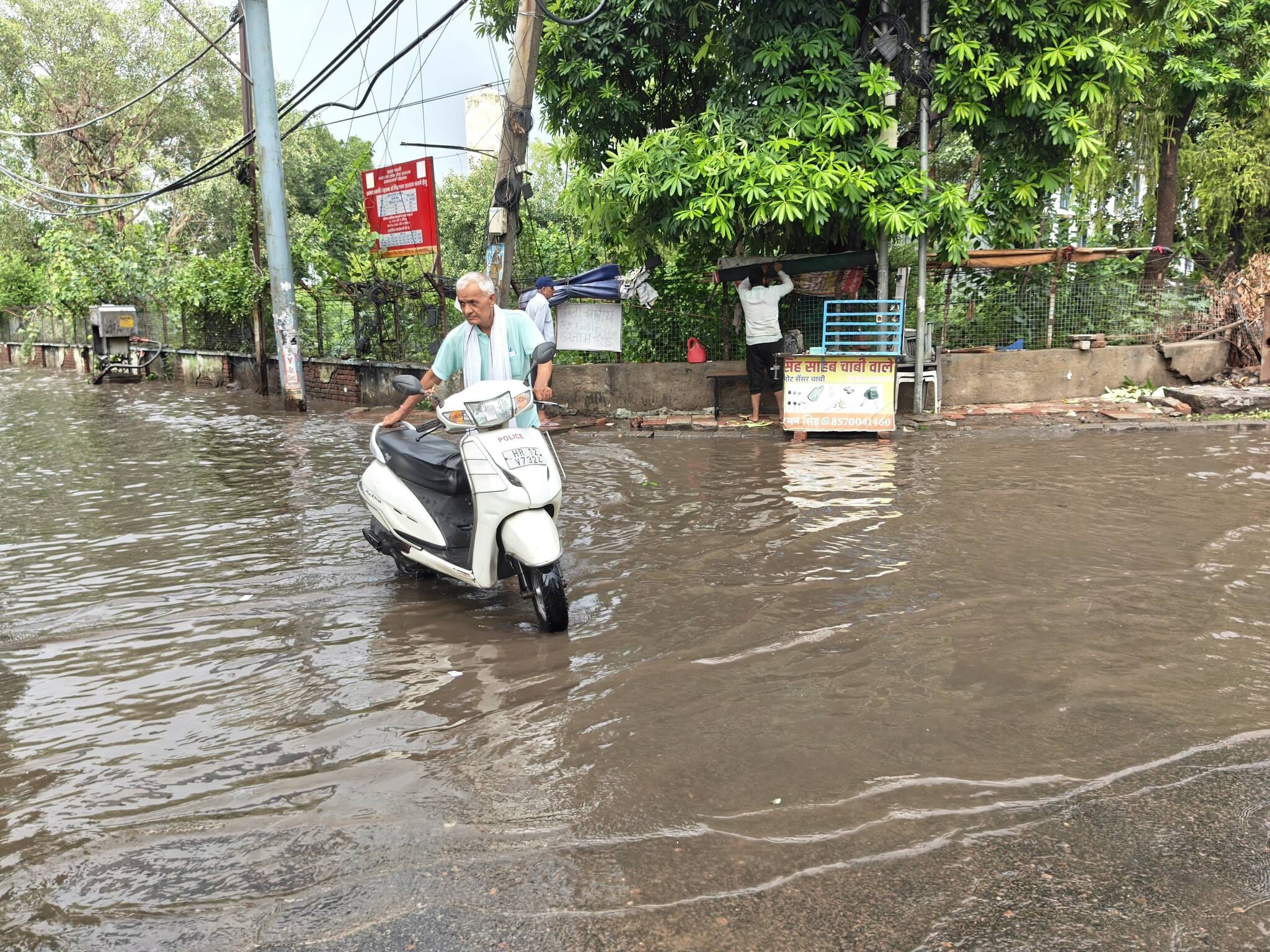 33-रोहतक के मॉडल टाउन स्थित डबल पार्क के पास जलभराव से बंद स्कूटी को लेकर जाता राहगीर। संवाद