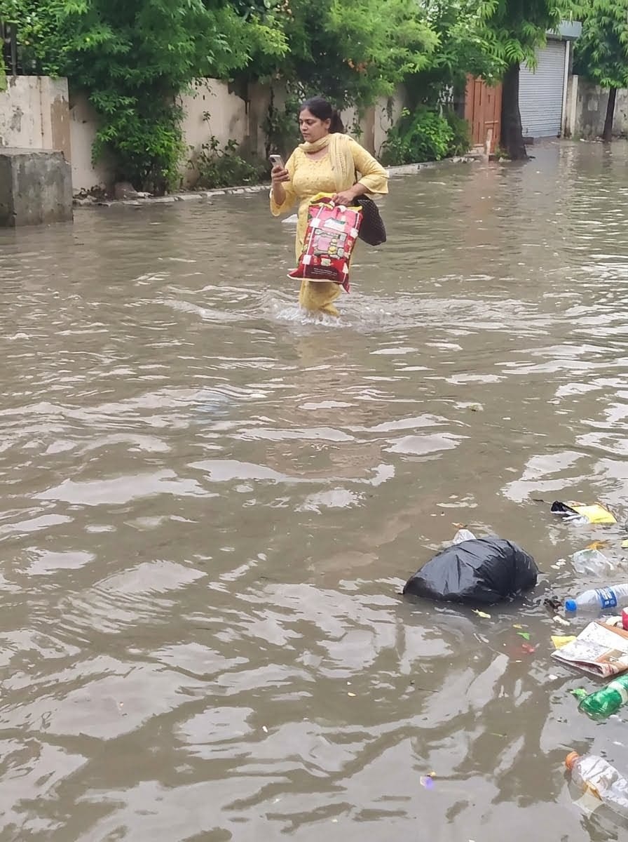 33-रोहतक के मॉडल टाउन स्थित डबल पार्क के पास जलभराव से बंद स्कूटी को लेकर जाता राहगीर। संवाद
