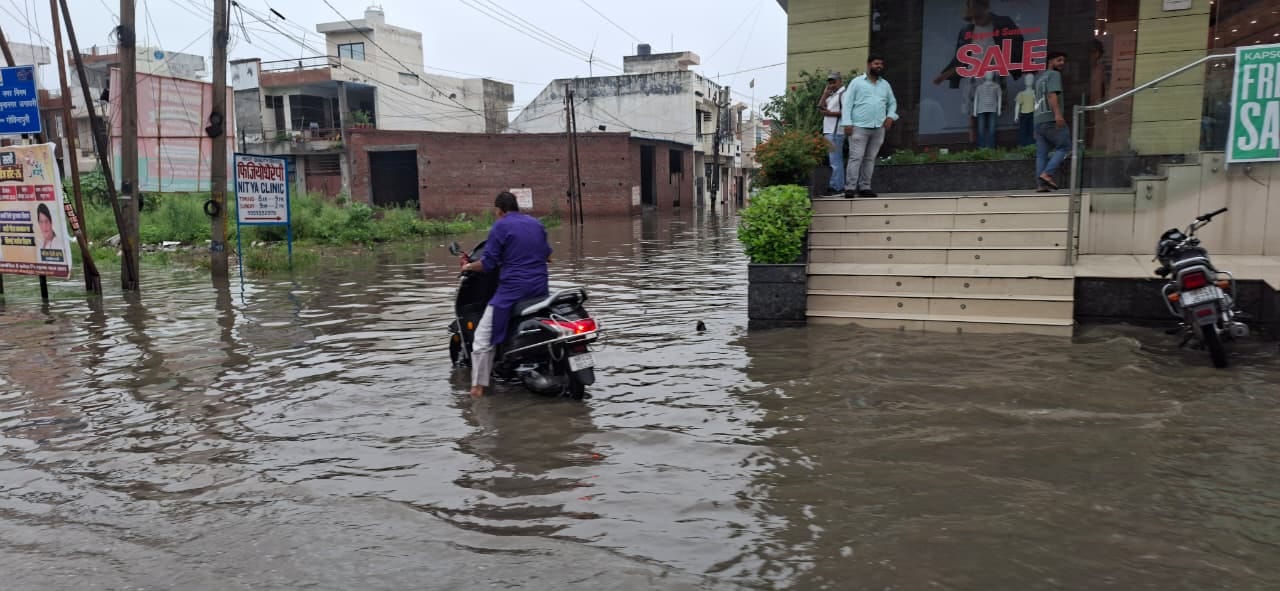 मटका चौक पर जलभराव के बीच से गुजरता कांवड़िया। संवाद