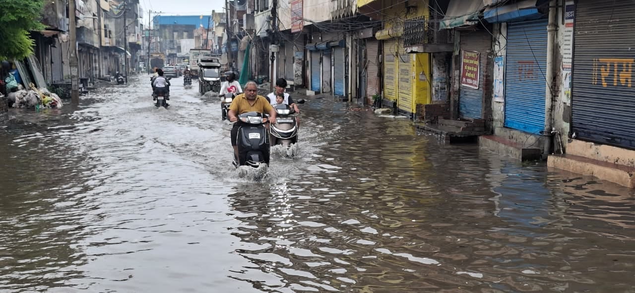 मटका चौक पर जलभराव के बीच से गुजरता कांवड़िया। संवाद