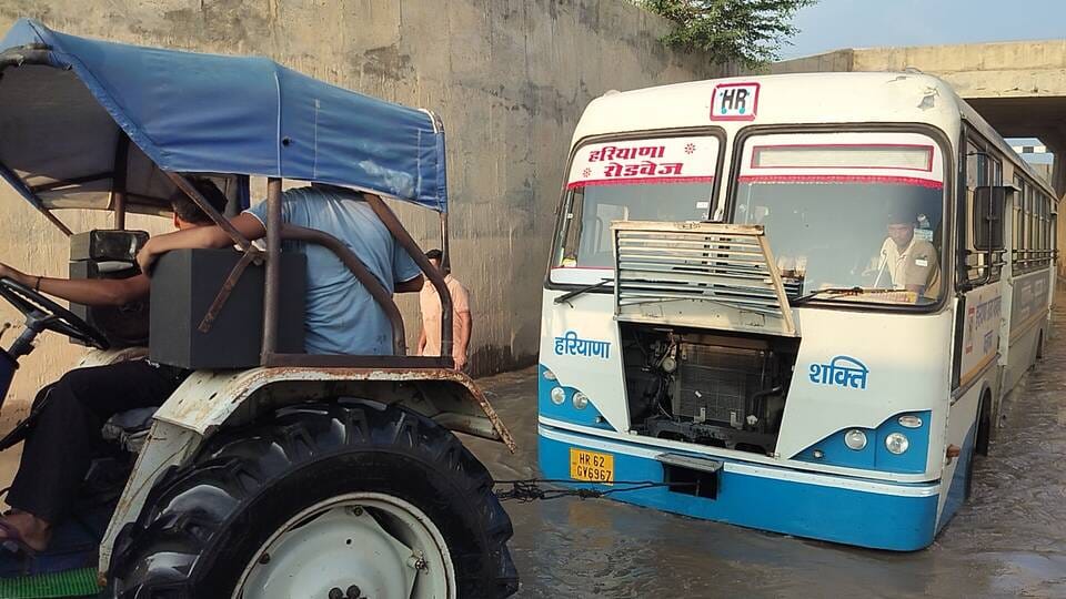 अमानी अंडरब्रिज में भरे पानी में फंसी बस और बस को निकालते हुए ग्रामीण