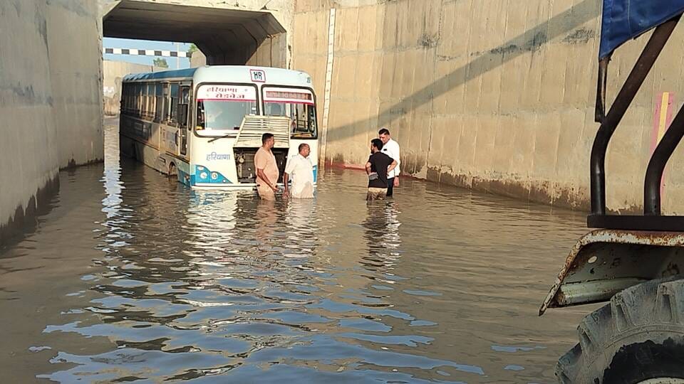 अमानी अंडरब्रिज में भरे पानी में फंसी बस और बस को निकालते हुए ग्रामीण