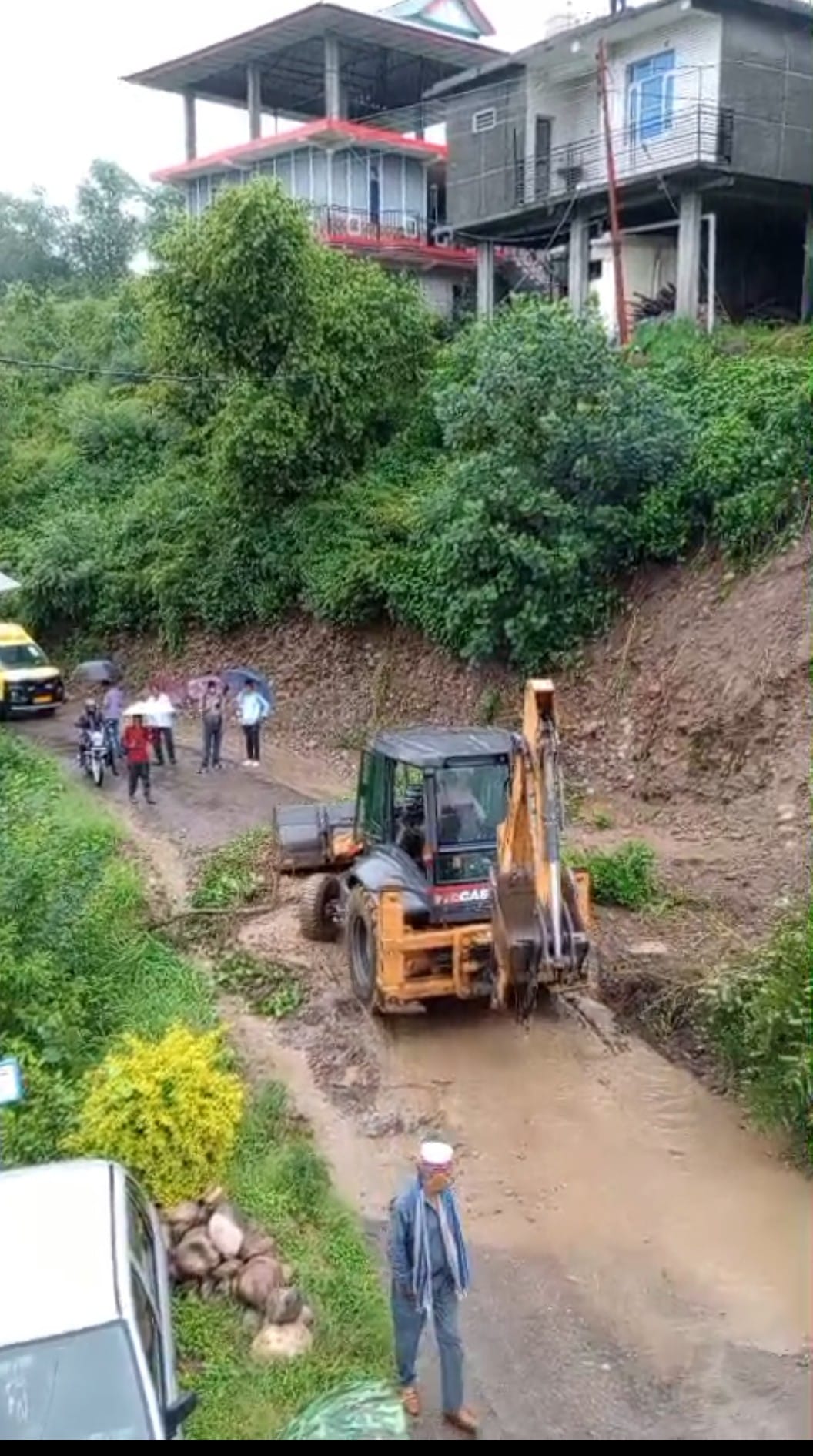 कश्मीर गांव में मुख्य सड़क के साथ भूस्खलन के कारण मकानों में घुसे मलबे से हुए नुकसान का आकलन कर