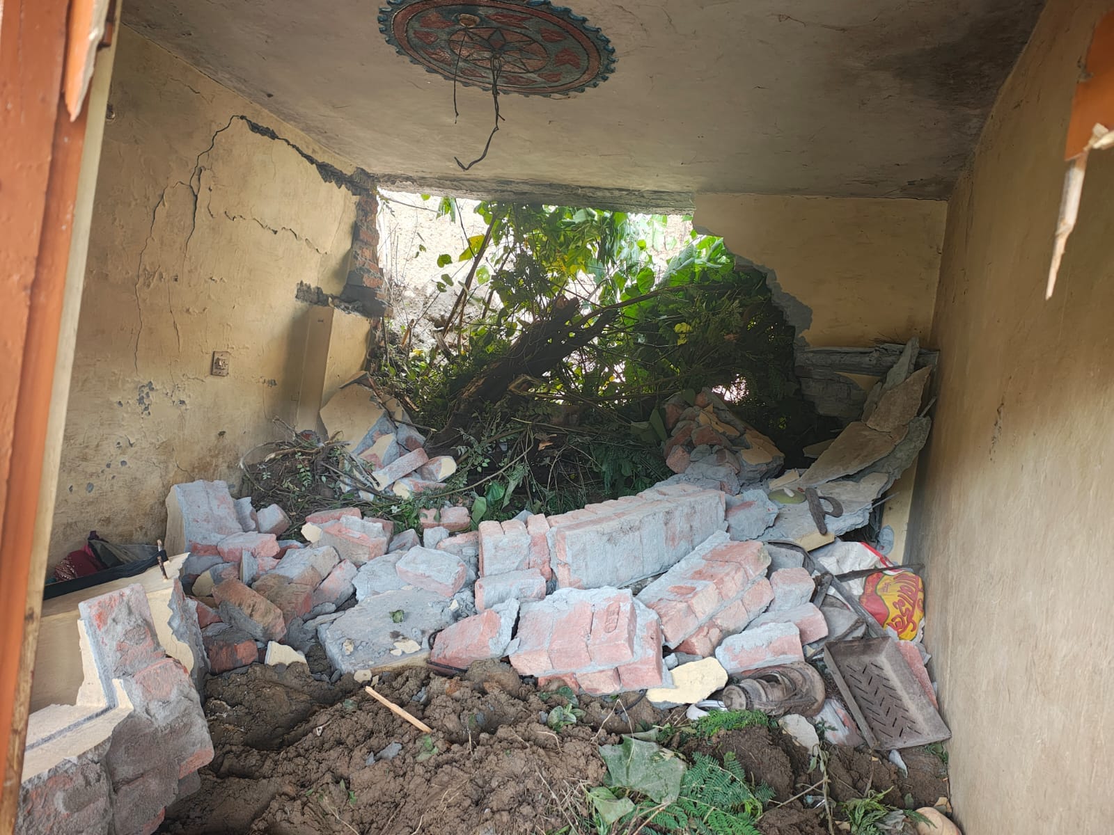 कश्मीर गांव में मुख्य सड़क के साथ भूस्खलन के कारण मकानों में घुसे मलबे से हुए नुकसान का आकलन कर