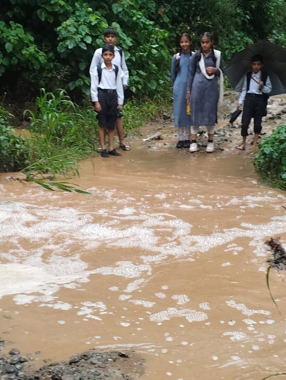 ग्राम पंचायत कचौली के बड्डू में स्कूली बच्चे को कंधे पर नाला पार कराता ग्रामीण। स्रोत: जागरूक प ग्राम पंचायत कचौली के बड्डू में स्कूली बच्चे को कंधे पर नाला पार कराता ग्रामीण। स्रोत: जागरूक प