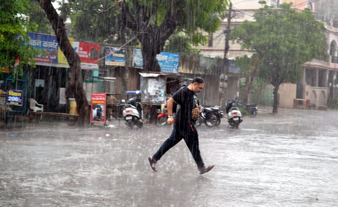 रविवार दोपहर को प्रेमनगर में बारिश के बीच दौड़ता युवक। संवाद