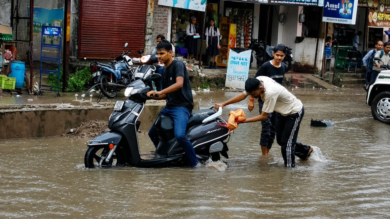 फोटो-26-इंदिरा नगर में जलभराव के बीच बेटी को स्कूल से लेकर लौटती महिला।