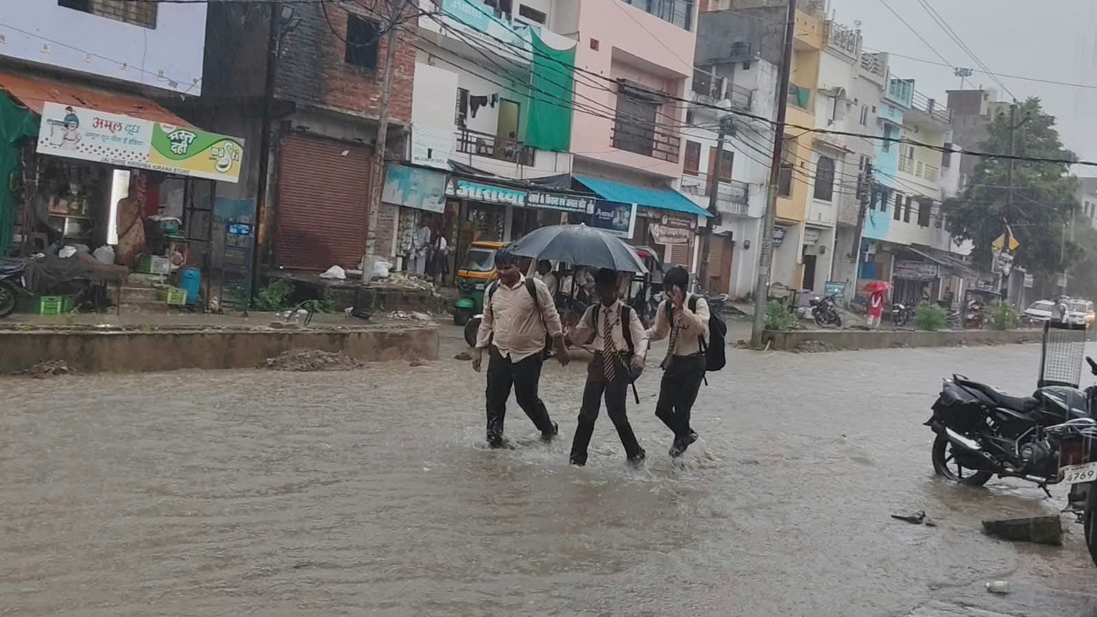 फोटो-26-इंदिरा नगर में जलभराव के बीच बेटी को स्कूल से लेकर लौटती महिला।