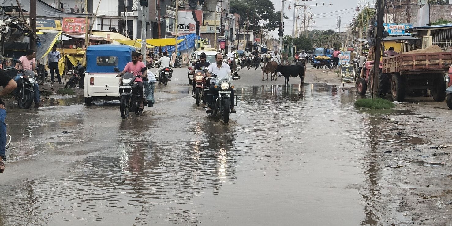 जनौरा में बारिश के बाद हुए जलभराव के बीच से होकर गुजरते वाहन।