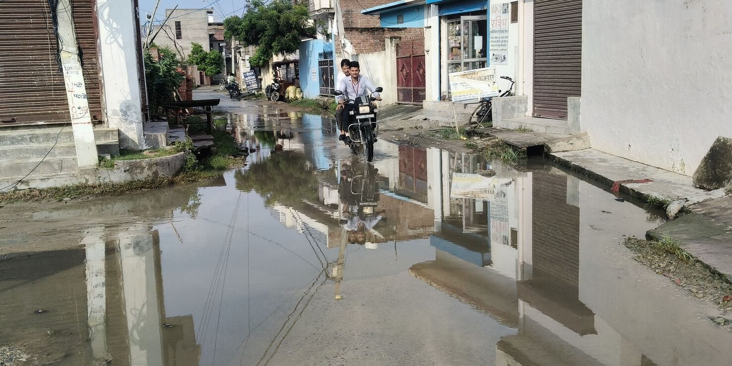 जनौरा में बारिश के बाद हुए जलभराव के बीच से होकर गुजरते वाहन।