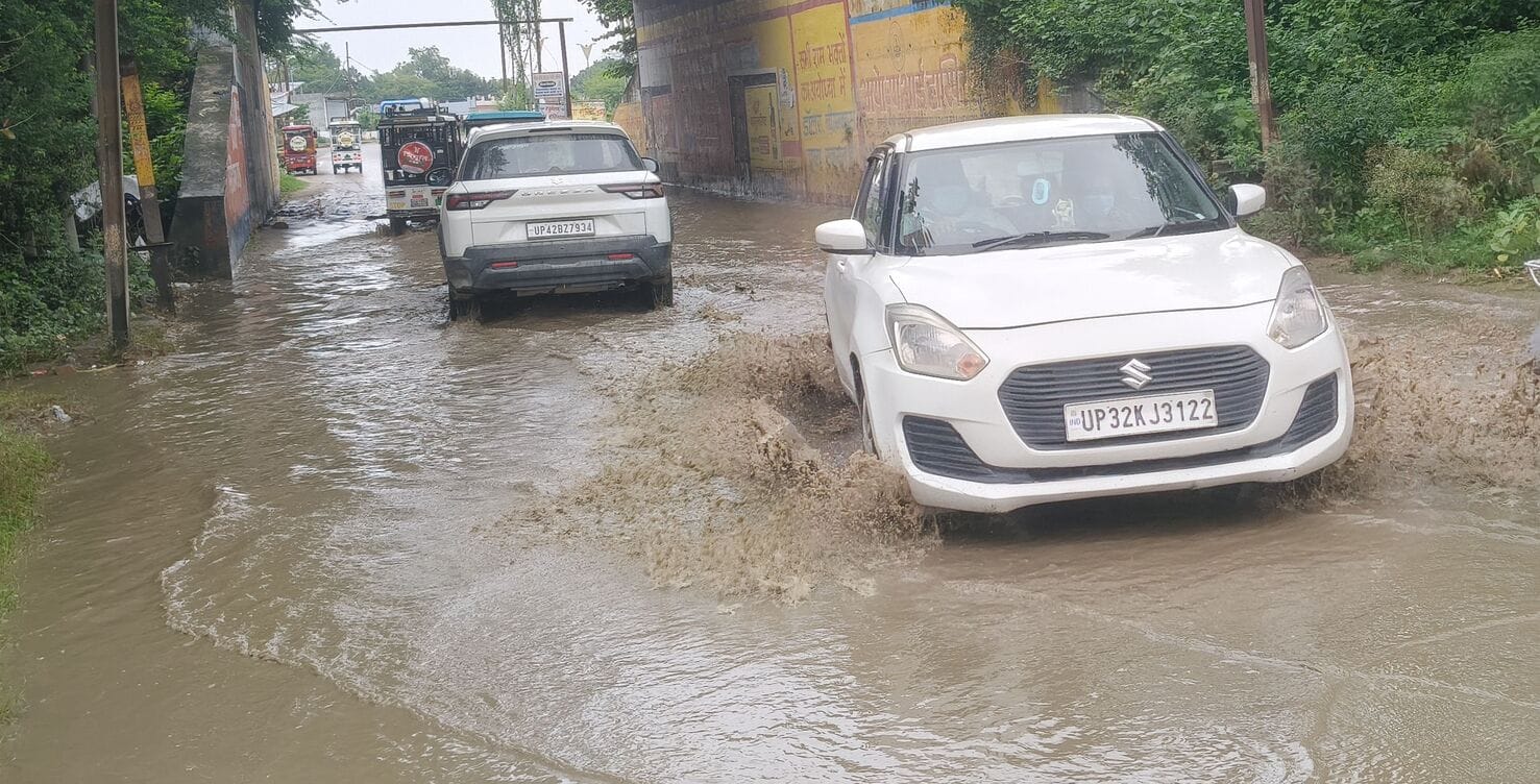 जनौरा में बारिश के बाद हुए जलभराव के बीच से होकर गुजरते वाहन।