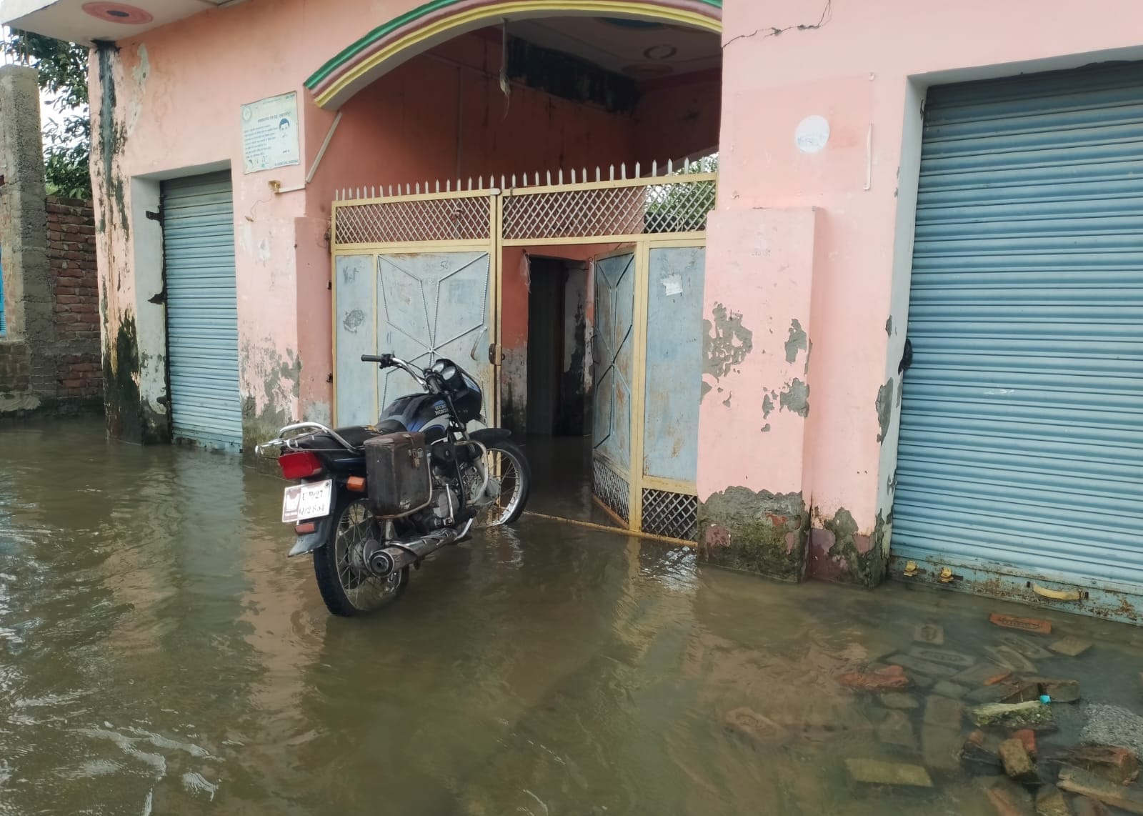 जलालाबाद-शमसाबाद स्टेट हाईवे पर भरे पानी से गुजरते लोग। संवाद
