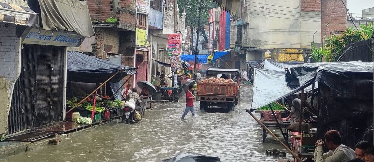 फोटो01बिलराम गेट लक्ष्मी सिनेमा के पास बारिश के दौरान जलभराव के बीच से होकर निकलते लोग। संवाद