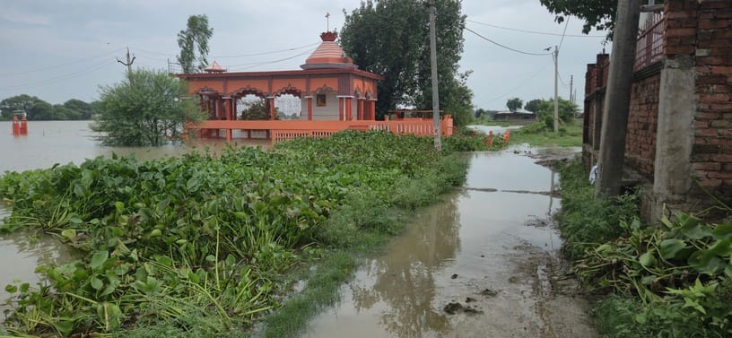 रेवतीपुर-रामपुर मार्ग पर फैले बाढ़ के पानी से गुजरते राहगीर। संवाद