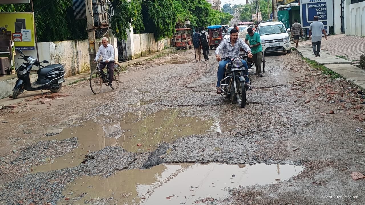 शहर के सिंचाई विभाग चौराहा के पास सड़क पर बने गड्ढों से बचकर निकलते राहगीर। संवाद