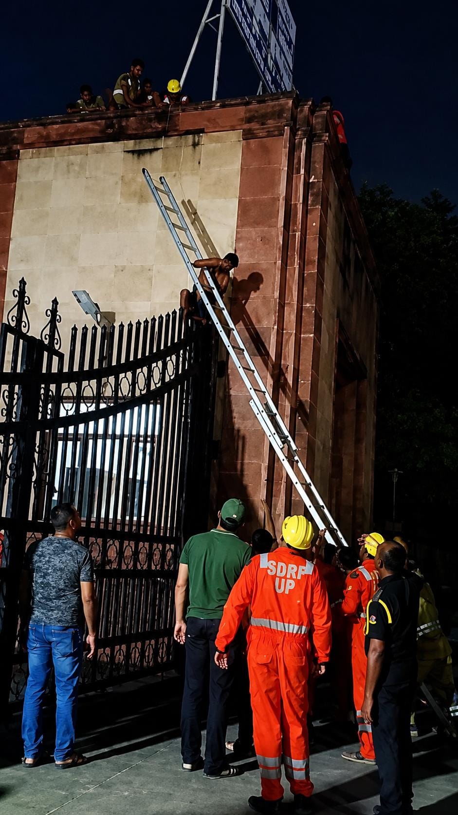 जाल बिछाकर व सीढ़ी लगाकर छात्र को गेट से उतारते पुलिस, दमकल व एसडीआरएफ की टीम।