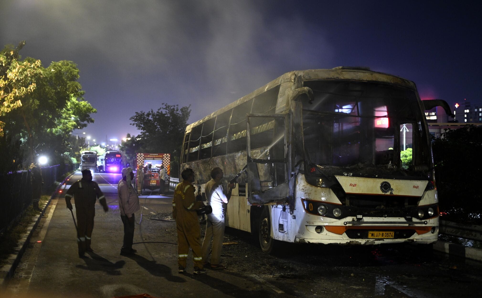 बस में आग लगने के बाद सड़क पर खड़े यात्री