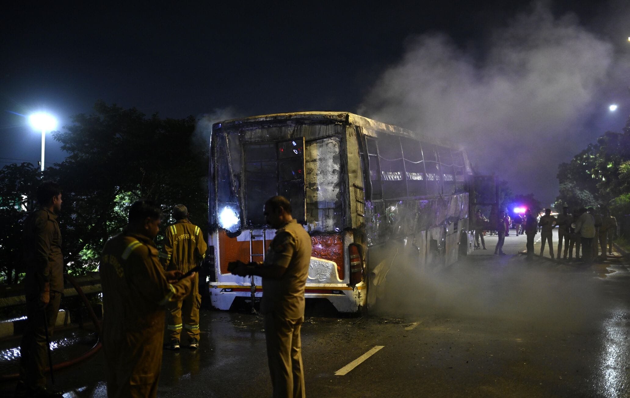 बस में आग लगने के बाद सड़क पर खड़े यात्री