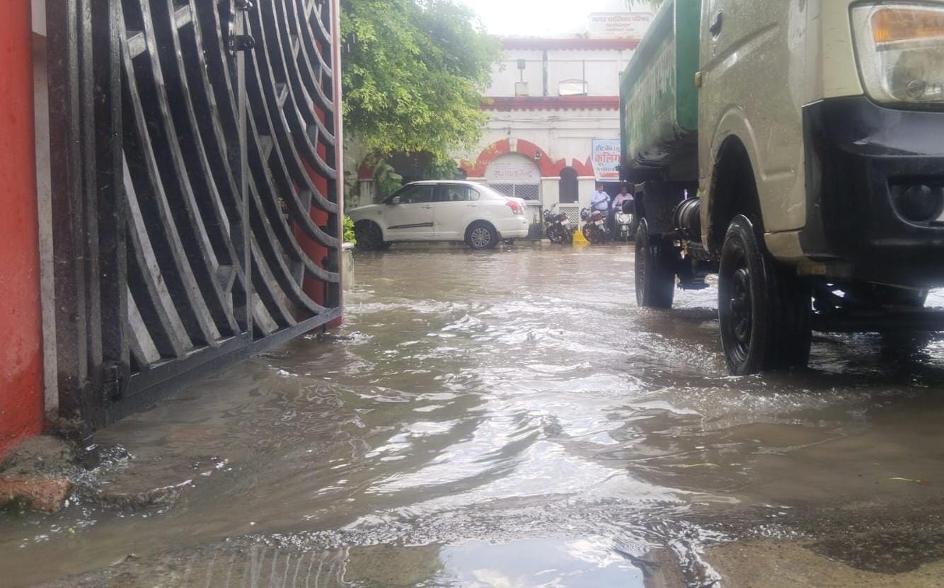 जलभराव के बीच निकलते स्कूली बच्चे व राहगीर। संवाद