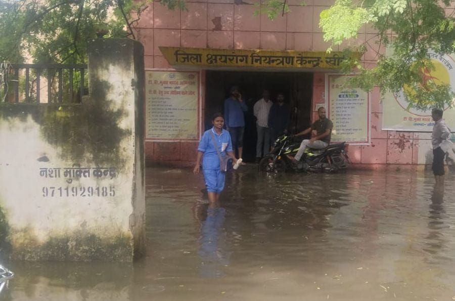 जलभराव के बीच निकलते स्कूली बच्चे व राहगीर। संवाद