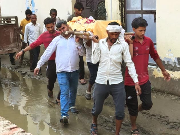 गांव से कीचड़ में अंतिम यात्रा निकलने के बाद सफाई करते सफाई कर्मी। संवाद