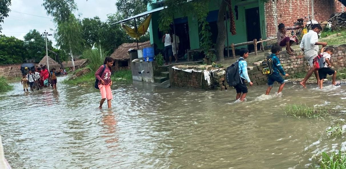 फोटो 38- नगला जयकिशन में बाढ़ के पानी के बीच हाथों में चप्पल लेकर स्कूल जाता छात्र। स्रोत संव