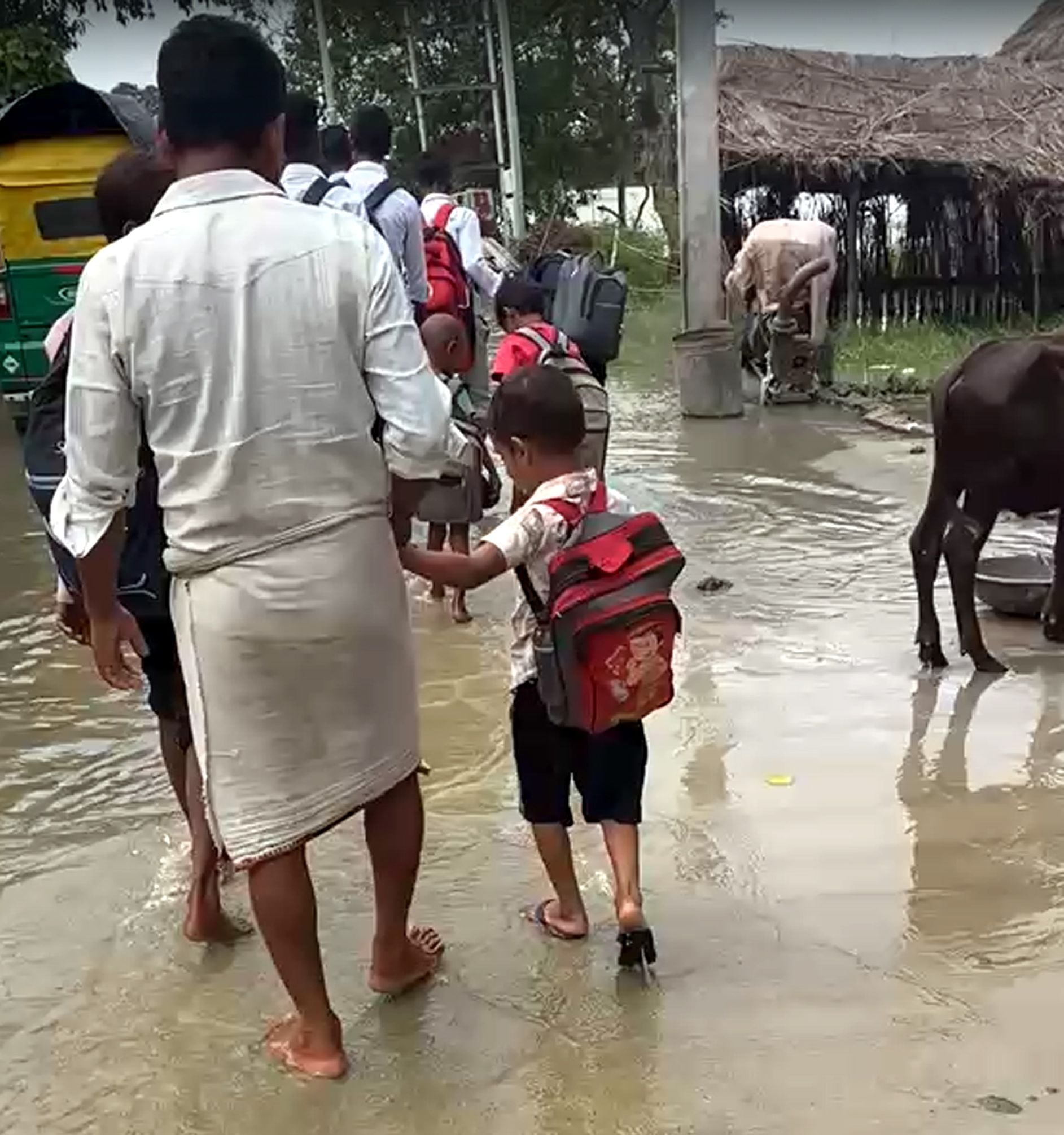 फोटो 38- नगला जयकिशन में बाढ़ के पानी के बीच हाथों में चप्पल लेकर स्कूल जाता छात्र। स्रोत संव