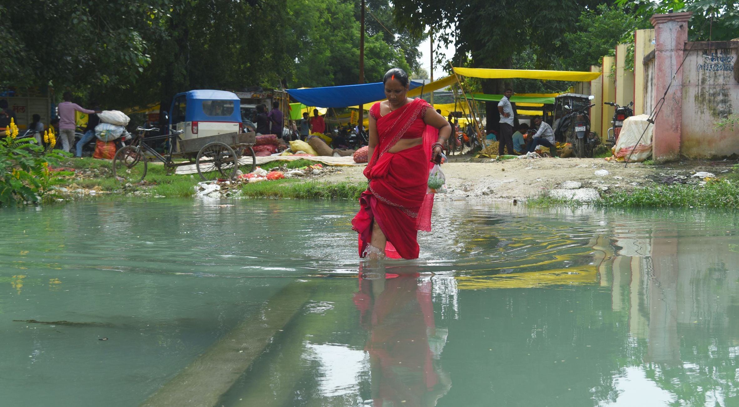 खंभे के सहारे नहर को पार करते लोग। 