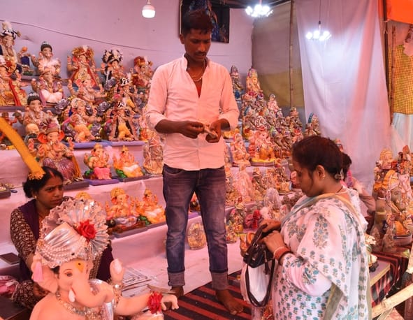 जानकारी देते गणेश प्राकट्य कमेटी के पदाधिकारी व गणपति की प्रतिमा खरीदकर घर ले जाते श्रद्धालु।