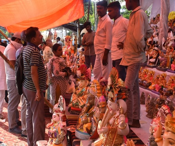 जानकारी देते गणेश प्राकट्य कमेटी के पदाधिकारी व गणपति की प्रतिमा खरीदकर घर ले जाते श्रद्धालु।
