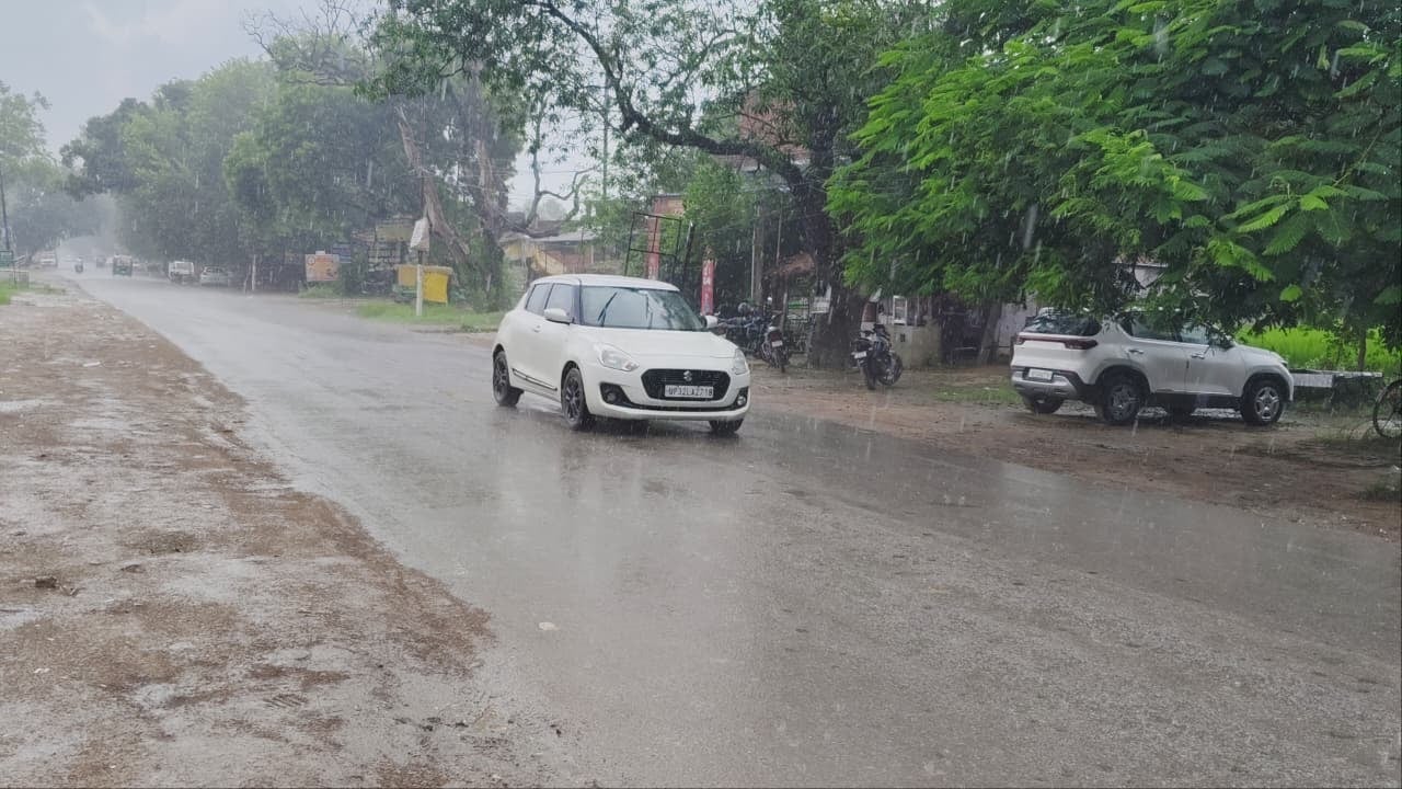 शहर के टांडा मार्ग पर बुधवार दोपहर बारिश के दौरान आवागमन करते वाहन में बैठे लोग। शहर के टांडा मार्ग पर बुधवार दोपहर बारिश के दौरान आवागमन करते वाहन में बैठे लोग।