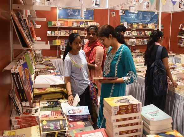 लखनऊ विश्वविद्यालय परिसर में आयोजित गोमती पुस्तक महोत्सव में किताबें देखते लोग।
