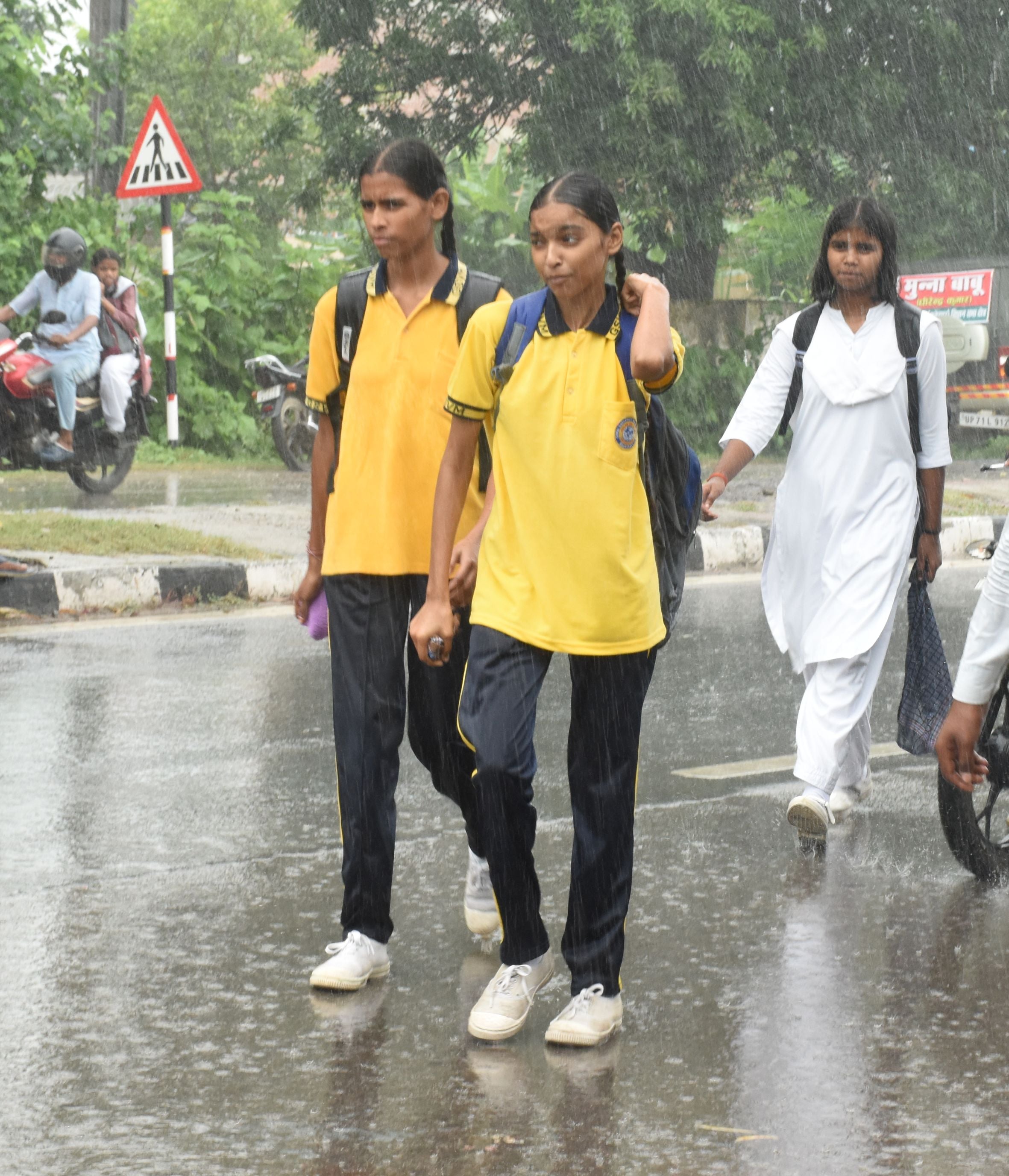 रतापुर चौराहा के पास बारिश में स्कूटी से बच्चे को लेकर जाती महिला। रतापुर चौराहा के पास बारिश में स्कूटी से बच्चे को लेकर जाती महिला।