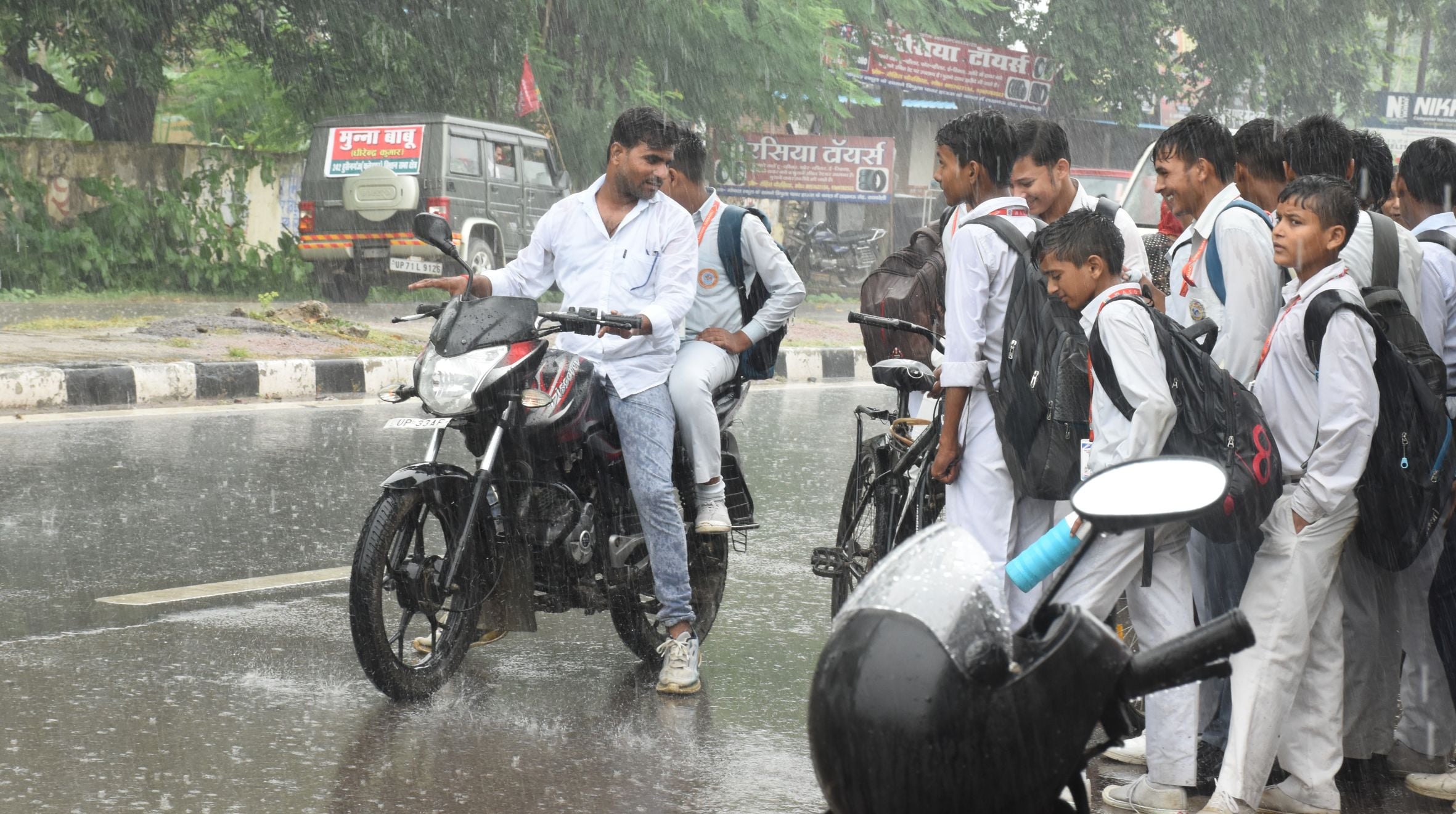 रतापुर चौराहा के पास बारिश में स्कूटी से बच्चे को लेकर जाती महिला। रतापुर चौराहा के पास बारिश में स्कूटी से बच्चे को लेकर जाती महिला।