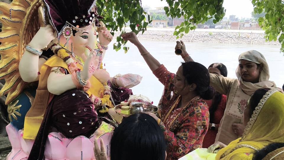 विसर्जन करने से पहले गणेश के कान में मन्नत बताती छोटी बच्ची। अशोक कुमार विसर्जन करने से पहले गणेश के कान में मन्नत बताती छोटी बच्ची। अशोक कुमार