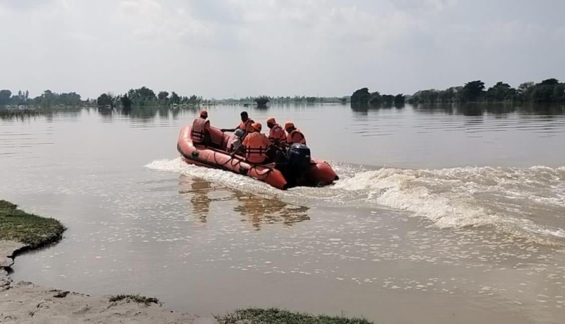 महिलाओं को रेस्क्यू कर नाव से उतारते एसडीआरएफ कर्मी व वीरपुर गांव में भरे पानी के बीच से निकलत महिलाओं को रेस्क्यू कर नाव से उतारते एसडीआरएफ कर्मी व वीरपुर गांव में भरे पानी के बीच से निकलत