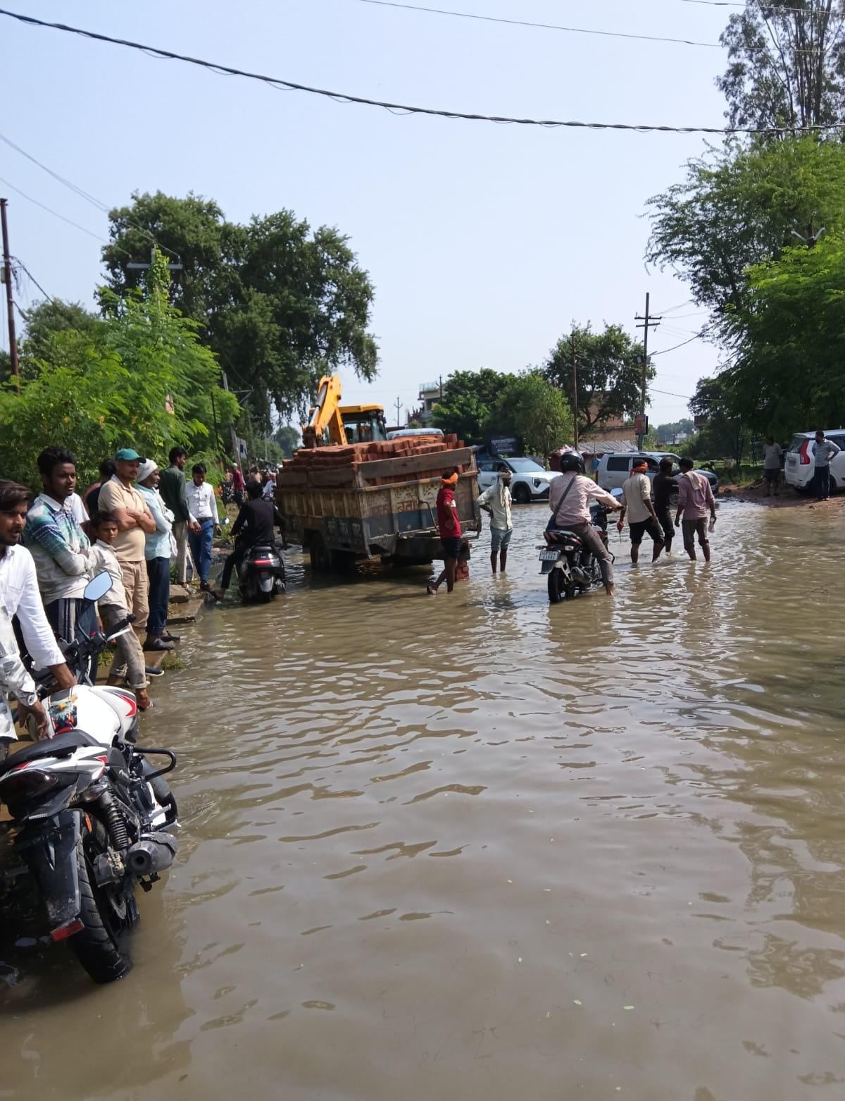 फोटो-20-बांदा-टांडा हाईवे पर हुए जलभराव और गड्ढों में फंसी ईंट लदी ट्राली। संवाद