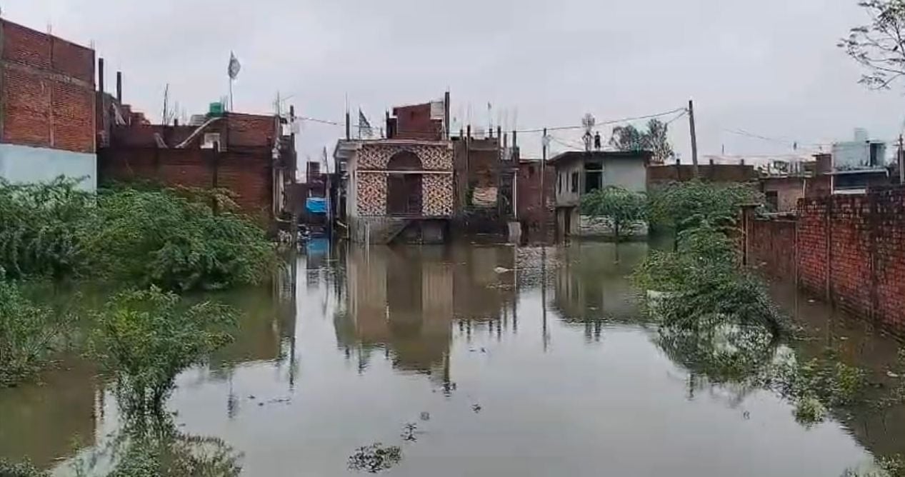 इंद्रानगर बजरंग चौराहे वाली गली में भरे पानी से निकलते लोग। संवाद