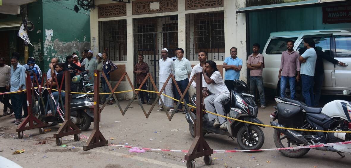 अपार्टमेंट के बाहर जुटे लोग और मरम्मत करते श्रमिक। अपार्टमेंट के बाहर जुटे लोग और मरम्मत करते श्रमिक।