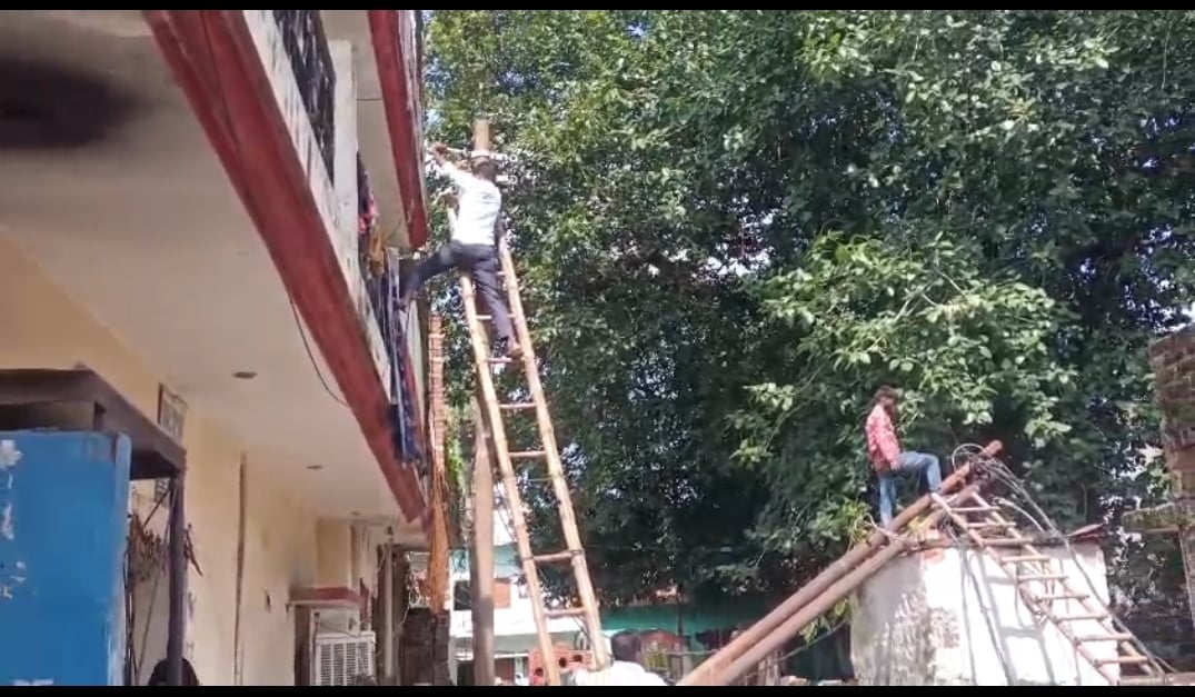 खंभा सही करते बिजली कर्मी।
