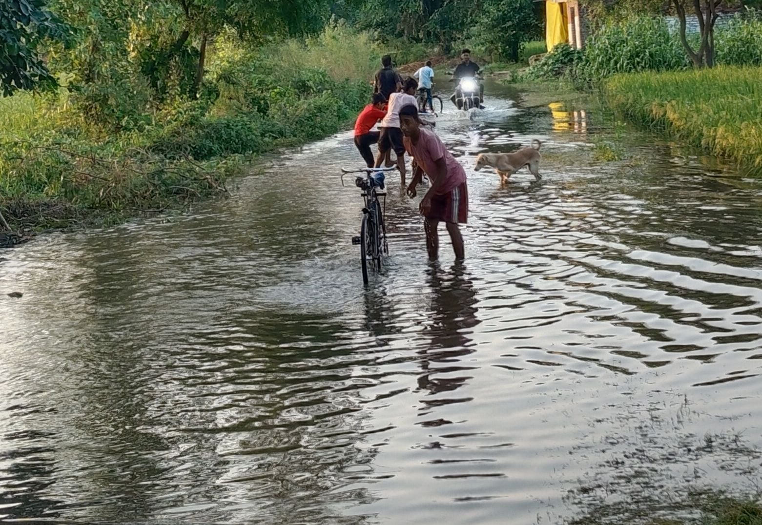 शिवनगर में भरे पानी में नाव से आवागमन करते बच्चे व महिला। संवाद
