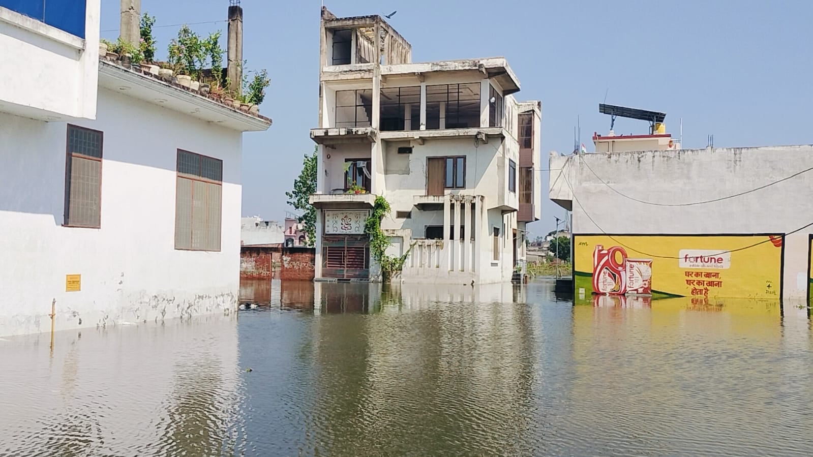 जलालाबाद में तिकोला घाट के आगे पानी में डूबी पुलिया से बाइक लेकर निकलता युवक। संवाद