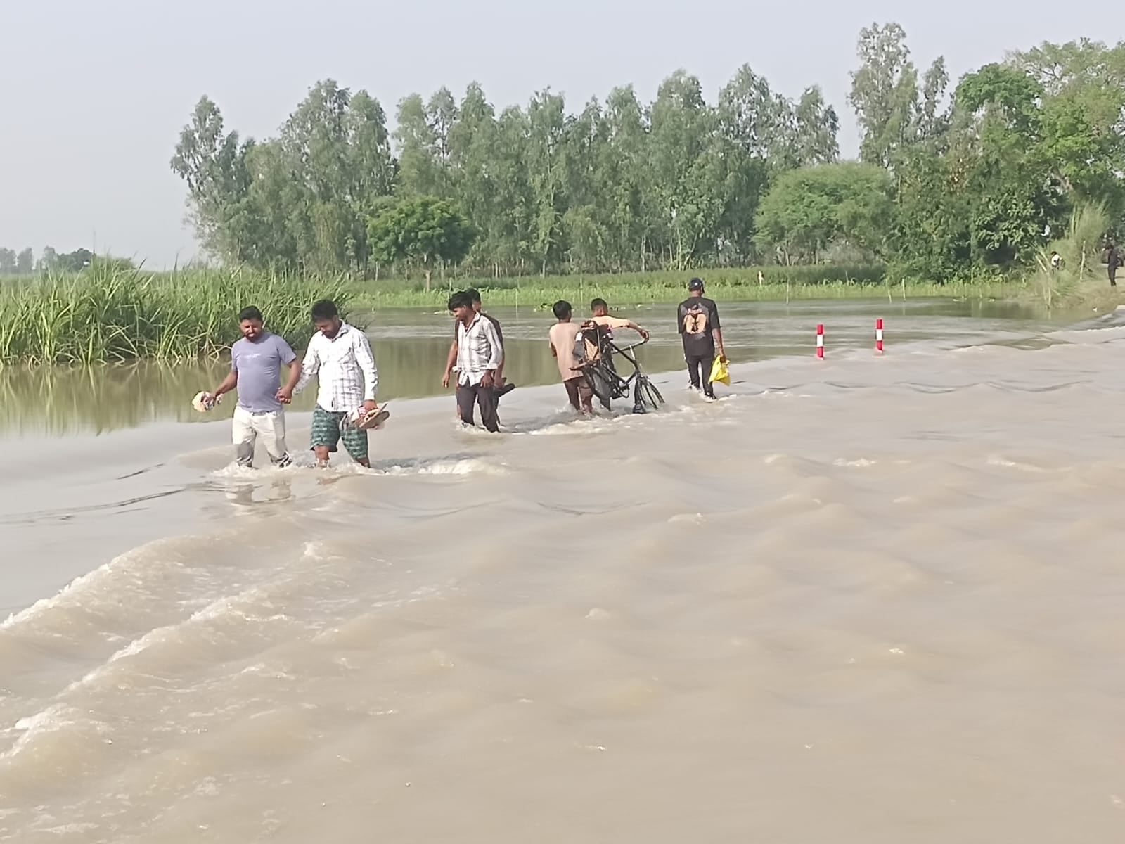 फोटो-26 गांव बरुआ को जाने वाली कटी सड़क पर भरे बाढ़ के पानी से निकलते लोग। संवाद फोटो-26 गांव बरुआ को जाने वाली कटी सड़क पर भरे बाढ़ के पानी से निकलते लोग। संवाद