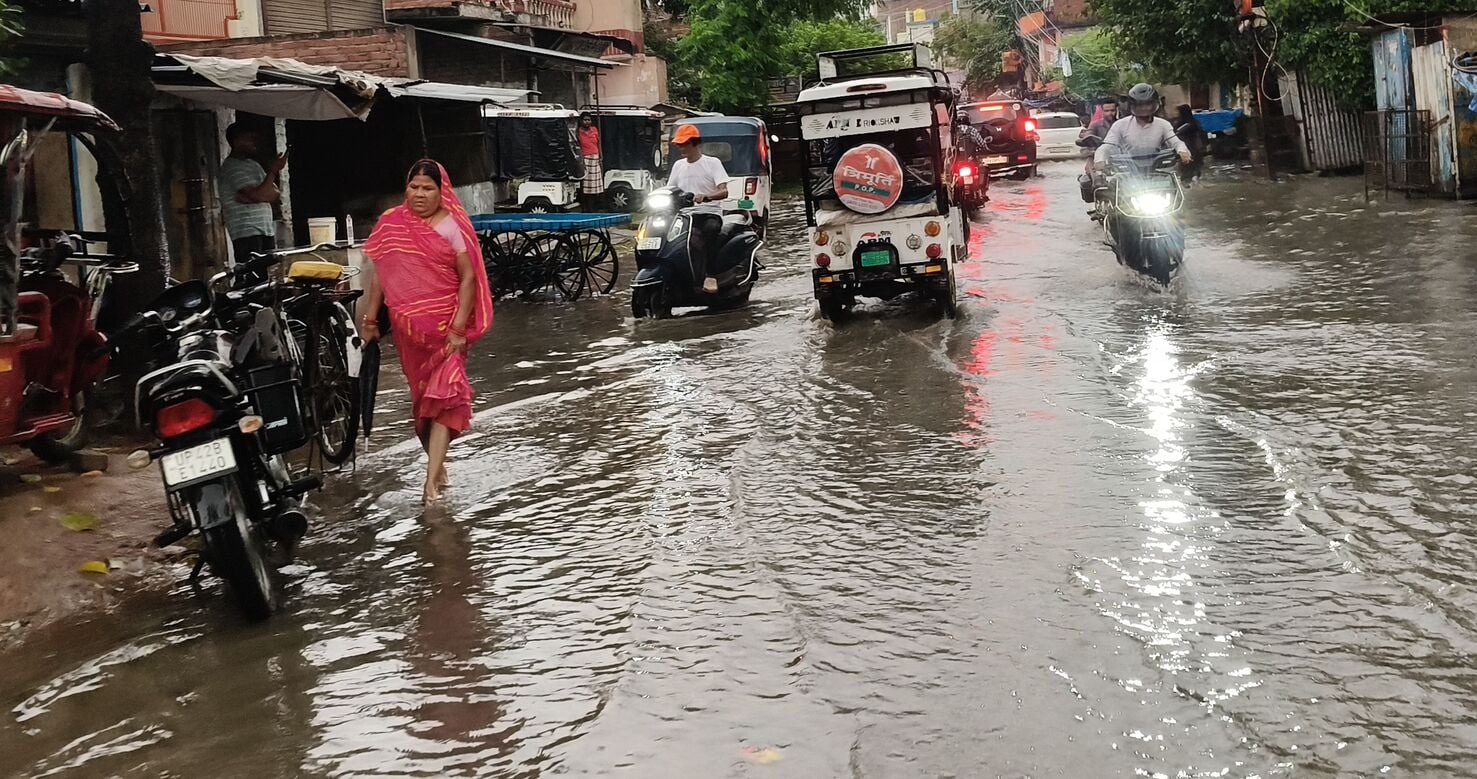 51-रिकाबगंज मुख्य मार्ग पर बारिश के दौरान हुए जलभराव से होकर गुजरता छात्र।-संवाद