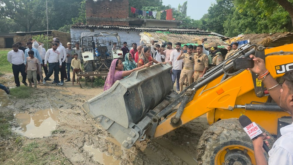 अकबरपुर के गौहन्ना के बबुरहिया गांव में जेसीबी मशीन को रोकतीं महिलाएं।