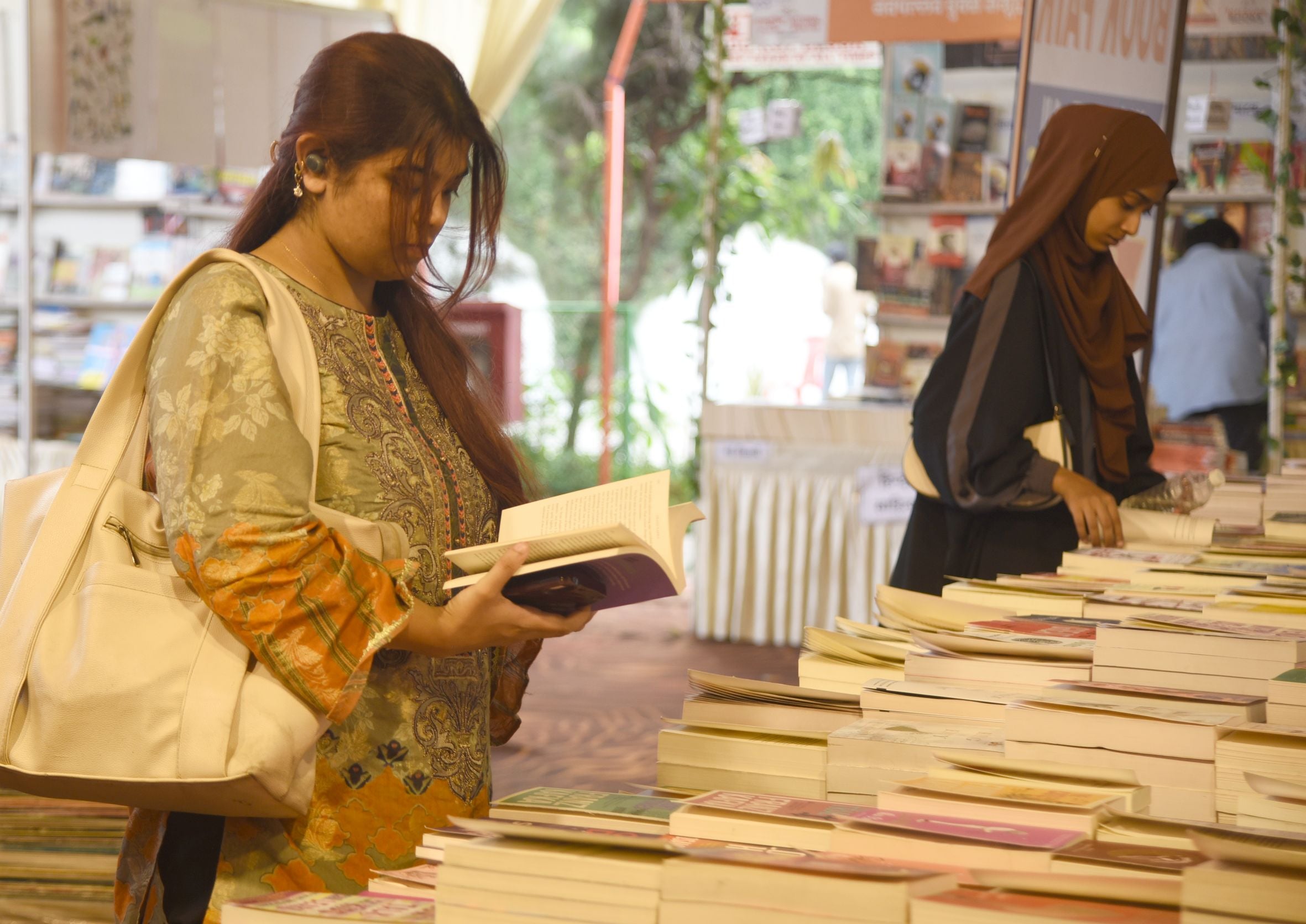 पुस्तक मेले में किताबें देखते लोग। पुस्तक मेले में किताबें देखते लोग।