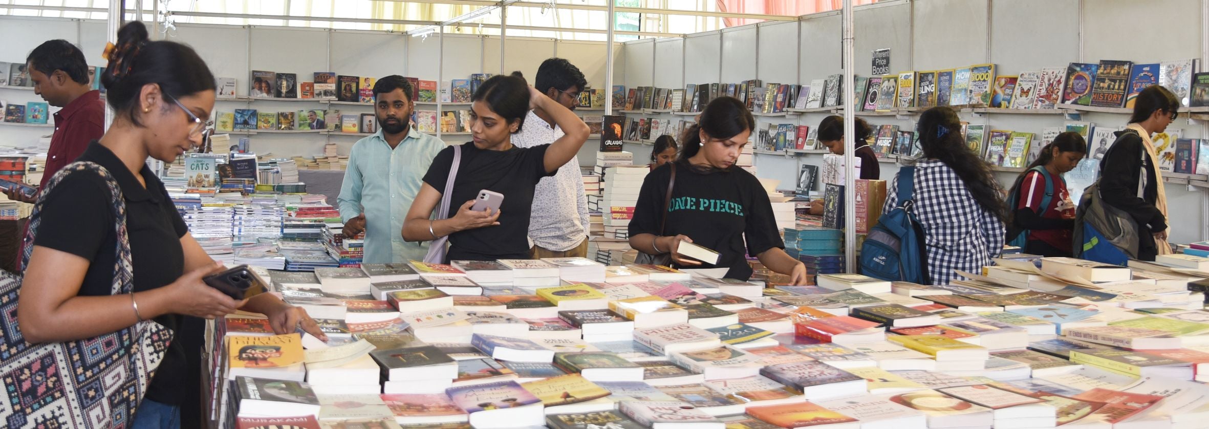 पुस्तक मेले में किताबें देखते लोग। पुस्तक मेले में किताबें देखते लोग।