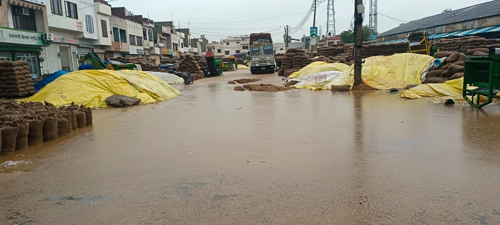 तिरपाल से ढकी धान की ढेरियां व भरा पानी। संवाद तिरपाल से ढकी धान की ढेरियां व भरा पानी। संवाद