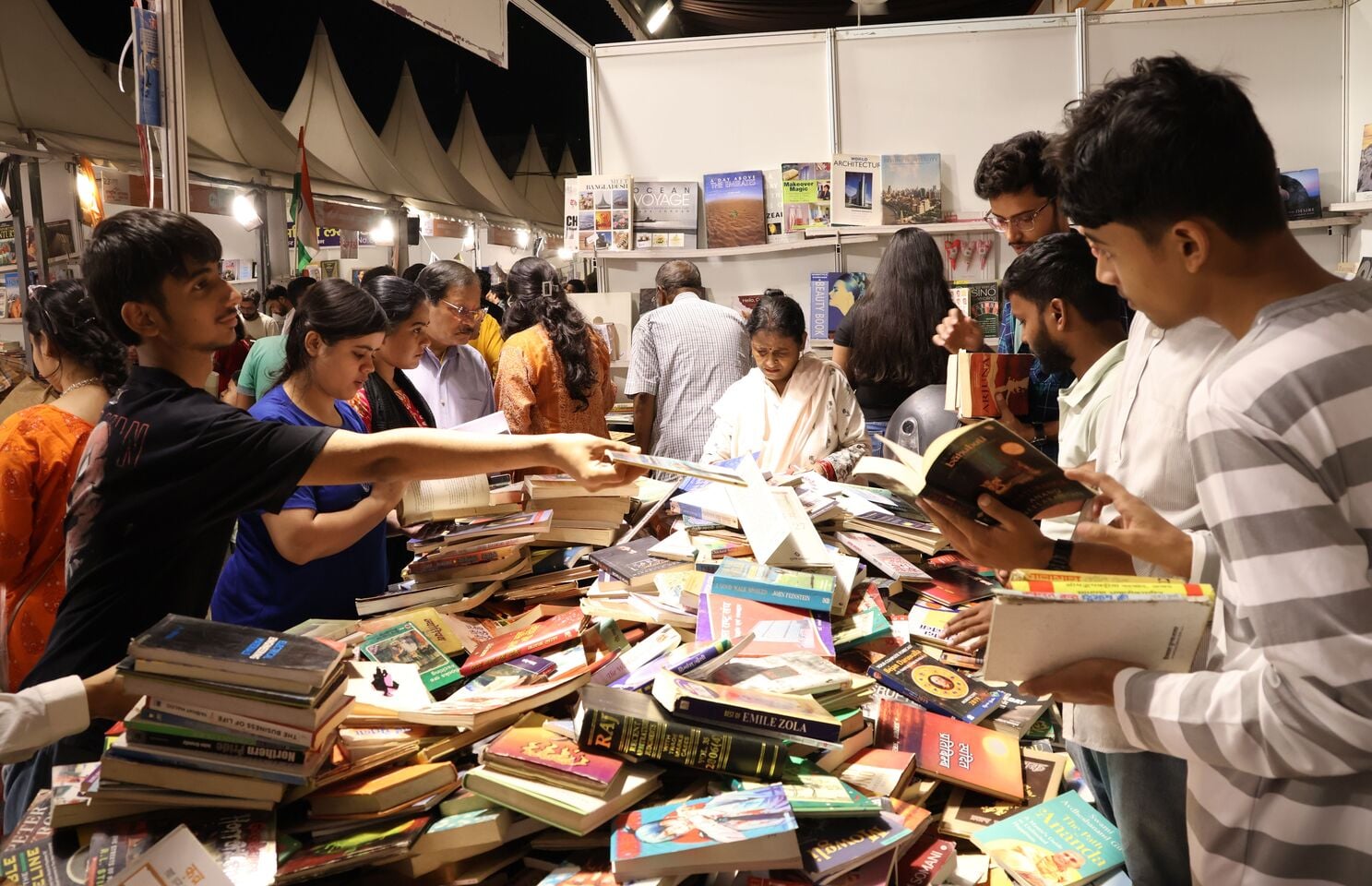 पुस्तक मेले में किताबें पसंद करते खरीदार। पुस्तक मेले में किताबें पसंद करते खरीदार।